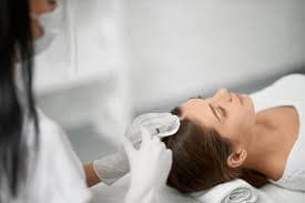 Dra. Rafaela Salvato, médica dermatologista em Florianópolis (CRM-SC 14.282 | RQE 10.934), avaliando couro cabeludo em consulta de tricologia premium